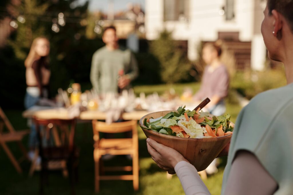 pexels-photo-5638275-5638275 A person holding a fresh salad bowl at an outdoor family gathering.